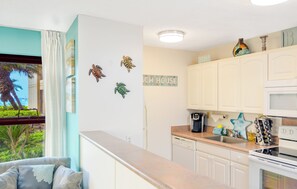 A kitchen with white cabinets, a coffee maker, and a star-shaped decoration on the wall. - Beachfront Resort - Ground Floor - Corner Unit - Steps to the Beach-Pool-Spa! (Kihei)