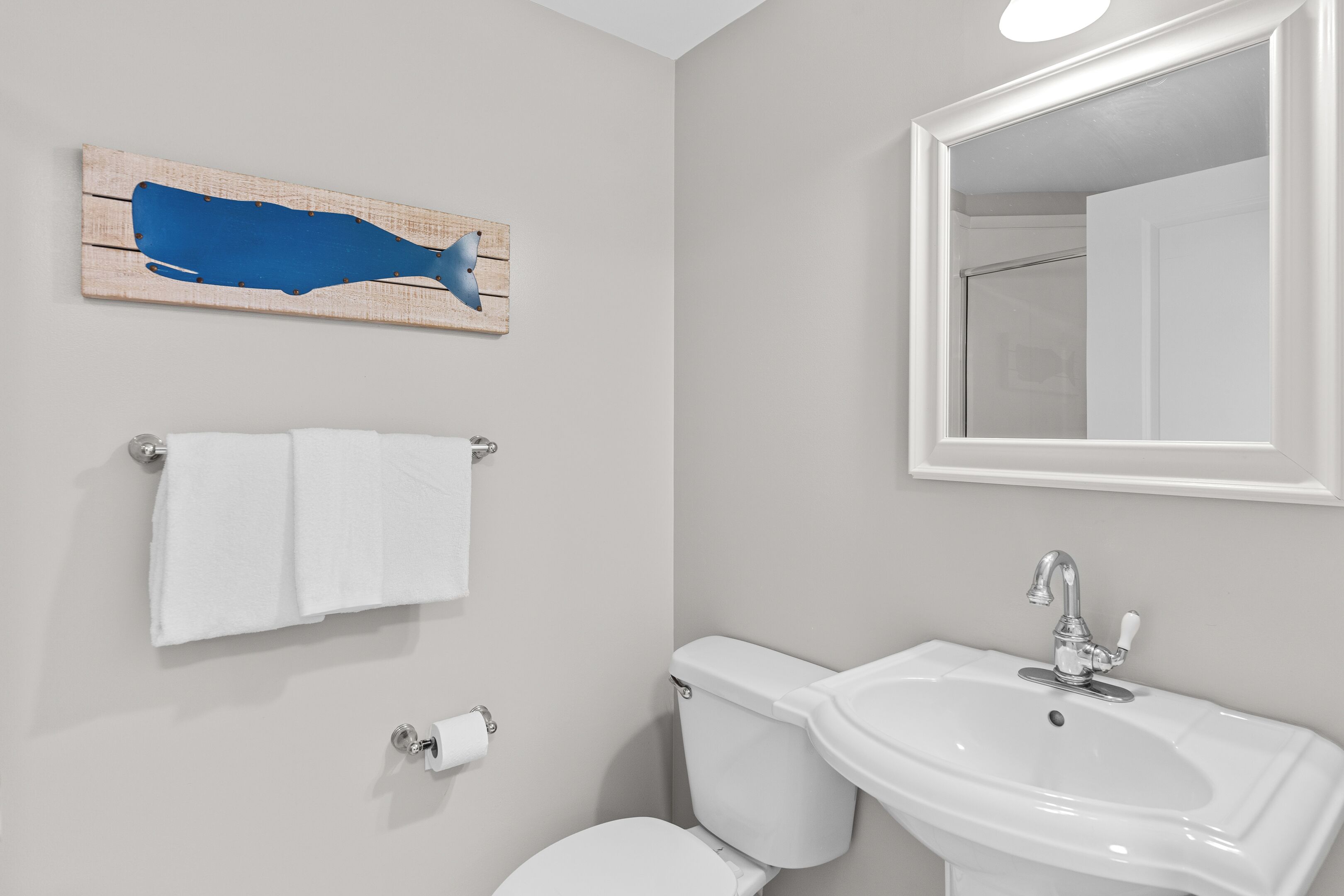 Ein Badezimmer mit Waschbecken, Toilette und einer Holzdekoration an der Wand.