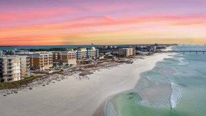 A coastal hotel with multiple buildings, a beach, and a pier.