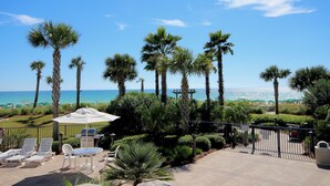 A patio area with outdoor seating, a grill, and a view of the beach.