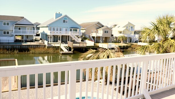 A waterfront property with multiple houses, a dock, and a white fence. - WATER FRONT, PRIVATE POOL, PET FRIENDLY, WIFI, OUTDOOR PARADISE! (North Myrtle Beach)