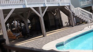 A covered outdoor area with a pool, wooden deck, and a staircase leading to a balcony. - WATER FRONT, PRIVATE POOL, PET FRIENDLY, WIFI, OUTDOOR PARADISE! (North Myrtle Beach)