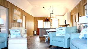 A living room with two light blue armchairs, a small white table, and a kitchen area in the background. - WATER FRONT, PRIVATE POOL, PET FRIENDLY, WIFI, OUTDOOR PARADISE! (North Myrtle Beach)