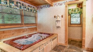 Ein Spa-Raum mit einer großen Holzwanne, Holzbalken und einer gefliesten Wand mit floralen Mustern.