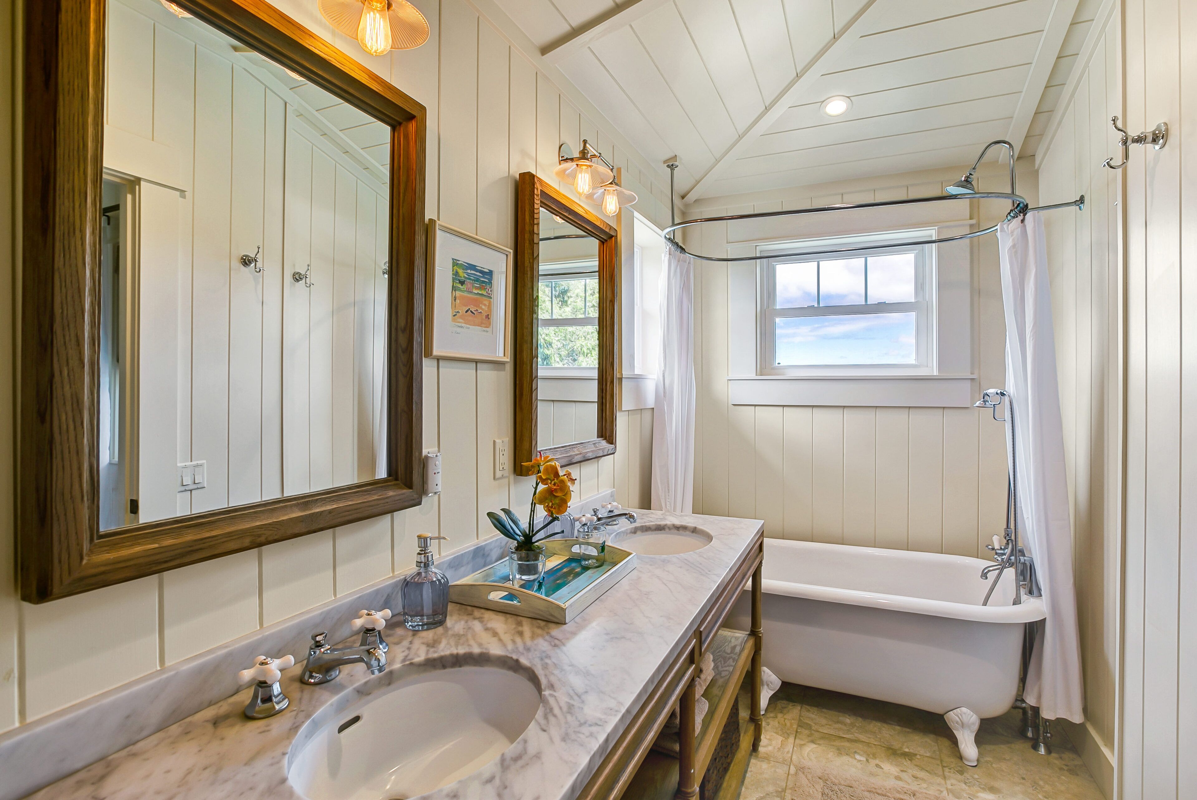Un bagno con due lavandini, uno specchio grande, una vasca e una finestra.