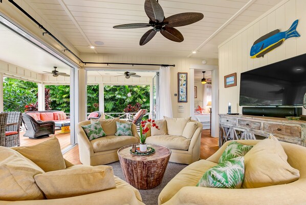A spacious living area with multiple sofas, a coffee table, and ceiling fans.