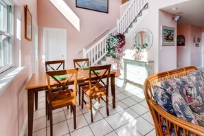 Relax in this spacious room with a dining area, wicker sofa, and staircase leading to an upper level.