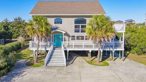 A two-story house with a blue door, a covered porch, and a staircase leading to the entrance. - Oceanside Dog Friendly Home w/ Hot Tub, Game Room, and Beach Nearby (Salvo)