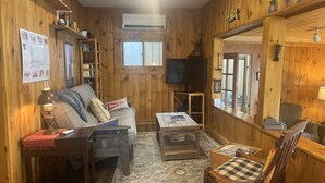 Un intérieur chaleureux en bois, avec un canapé, un téléviseur et une petite table.