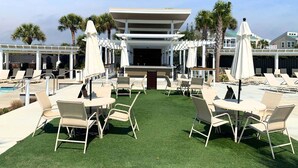 A poolside area with lounge chairs, a barbecue, and a covered seating area. - A Little Piece of Heaven by Sandpiper | Near Beach (Seabrook Island)