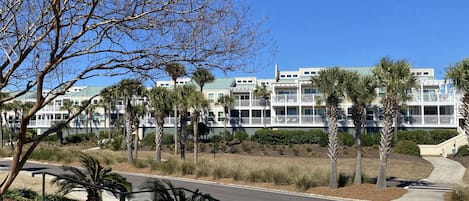 A multi-story hotel with balconies, palm trees, and a parking lot.