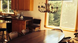 Une cuisine spacieuse avec des meubles en bois, une grande table à manger et un lustre.