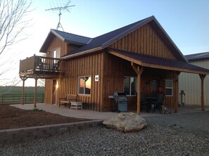 A wooden cabin with a balcony, a barbecue area, and a stone feature in the front. - Enjoy Cabin on working farm! 1 hr. Telluride, 1.5 hrs. Moab, UT. (Yellow Jacket)