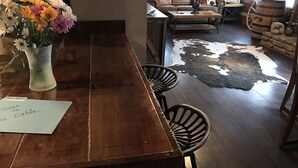 A wooden dining table with a welcome note, a vase of flowers, and a cowhide rug. - The Cabin at Flat Rock Farms - rustic charm on a beautiful former horse farm  (Lewisburg)