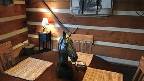 A rustic wooden dining area with a horse statue centerpiece, a table lamp, and a framed horse painting on the wall. - The Cabin at Flat Rock Farms - rustic charm on a beautiful former horse farm  (Lewisburg)