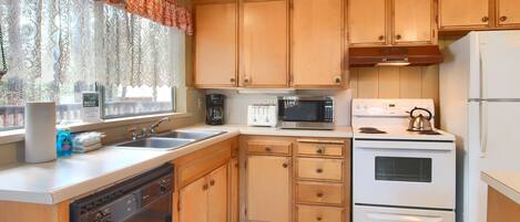 A kitchen with wooden cabinets, a dishwasher, a microwave, a stove, and a refrigerator.