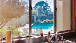 Una cocina con un amplio ventanal que da a un patio trasero con piscina.