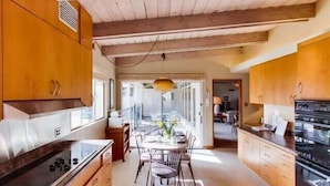 Una cocina moderna con armarios de madera, una mesa de comedor con sillas y vistas al salón.