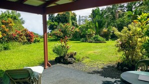 A covered outdoor seating area with a view of a lush garden.