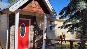 A house with a red door, stone wall, and a number '1305' on the side. - COMY, COZY COTTAGE! HOT TUB ! PETS BY APPROVAL 
BEAUTIFUL IN THE FALL! BOOK NOW (Ruidoso)