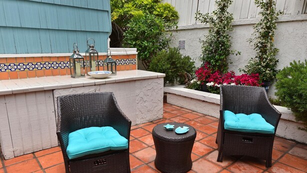 Two wicker chairs with teal cushions and a small round table with teal coasters, set on a tiled patio with a tiled backsplash and potted plants. - Crown Point Beach House - Beach and Water on 3 Sides! (San Diego)