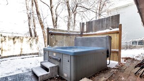 Een jacuzzi in een achtertuin met een houten omheining en een trap er naartoe.