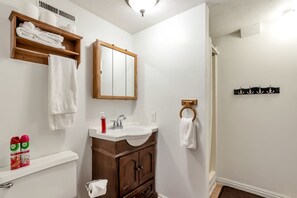Ein Badezimmer mit einem Holzbadezimmermöbel, einem Spiegel, einem Waschbecken und einem Handtuchhalter.