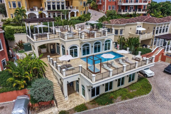 A multi-story building with a rooftop pool, outdoor seating, and a covered patio area.