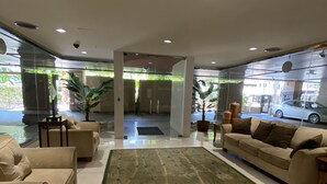 Um hall moderno com um tapete grande e estampado, dois sofás e um painel de vidro.