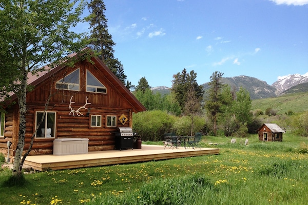 Grpa's cabin side yard, entrance to cabin, log playhouse, fire pit, and creek