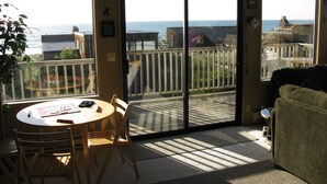 A room with a balcony, a round table with chairs, and a view of the sea. - Gorgeous Ocean Views and just steps to the beach! Book Now! (Watsonville)