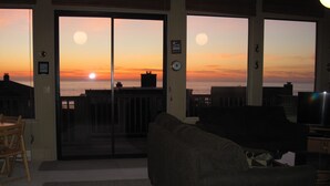 A living room with a large sliding glass door leading to a balcony overlooking the ocean at sunset. - Gorgeous Ocean Views and just steps to the beach! Book Now! (Watsonville)