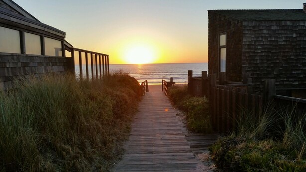 A wooden pathway leading to a beach with a sunset in the background. - Gorgeous Ocean Views and just steps to the beach! Book Now! (Watsonville)