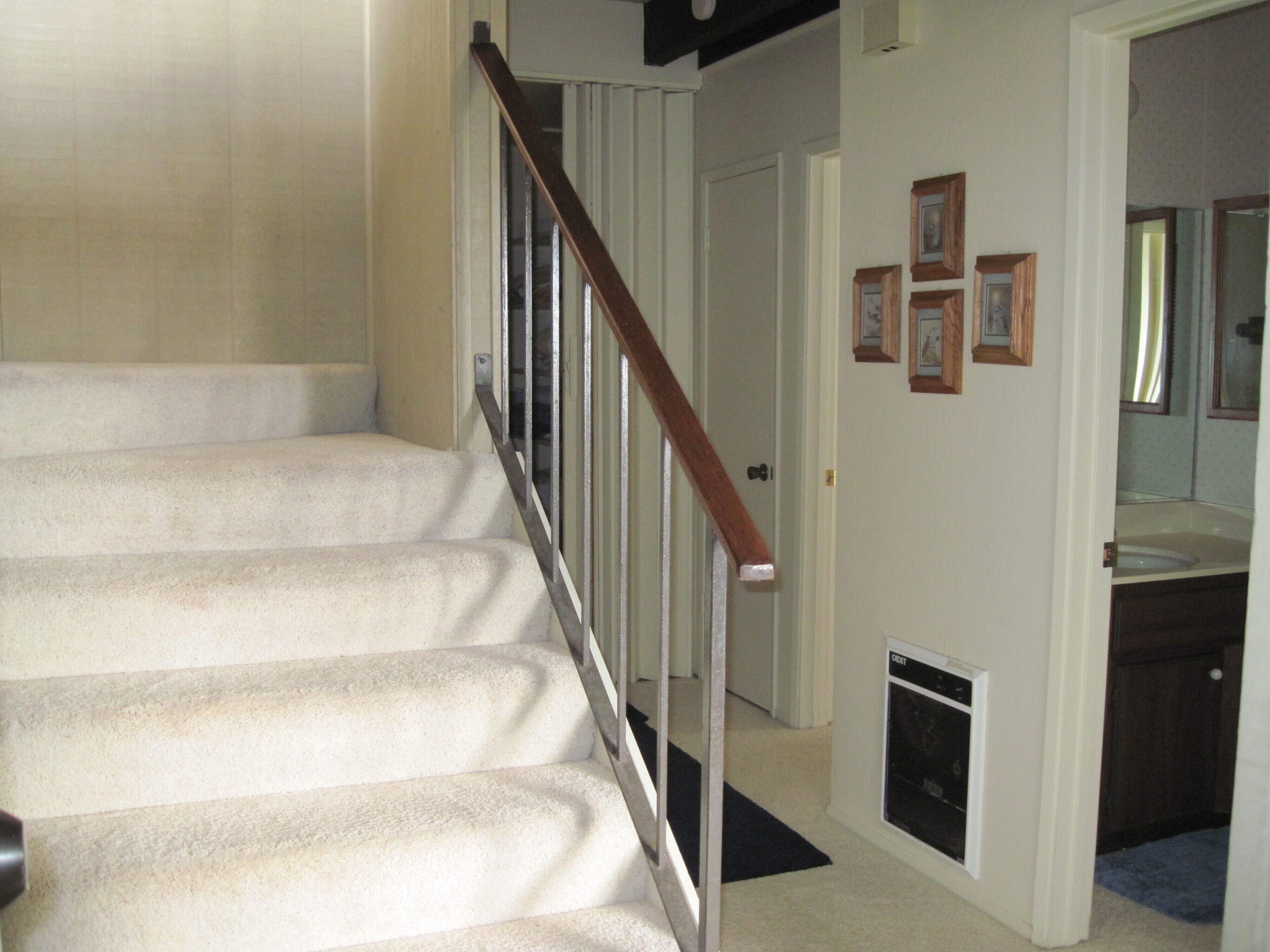 A staircase with a wooden handrail leading to a door.