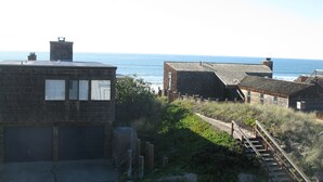 A coastal building with a view of the sea, featuring a staircase leading to a wooden deck. - Gorgeous Ocean Views and just steps to the beach! Book Now! (Watsonville)