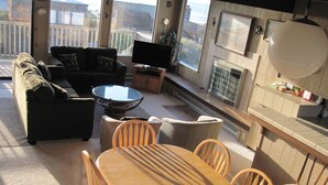 A sunlit living room with a sofa, TV, and dining area. - Gorgeous Ocean Views and just steps to the beach! Book Now! (Watsonville)