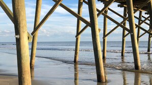 A wooden pier structure extending over a sandy beach with the ocean in the background. - Beautiful Southport, Golf Frontage & Oak Island Beach club .New Quartz counters  (Southport)