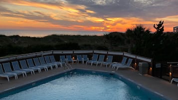 Relax by the pool surrounded by lounge chairs and lush vegetation.