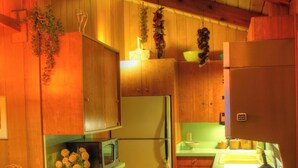 Una cocina funcional con armarios de madera, un refrigerador, un microondas y un lavamanos.
