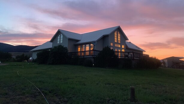 Une grande maison à deux étages, dotée d’un toit à pignon bien visible et d’un porche à l’avant.