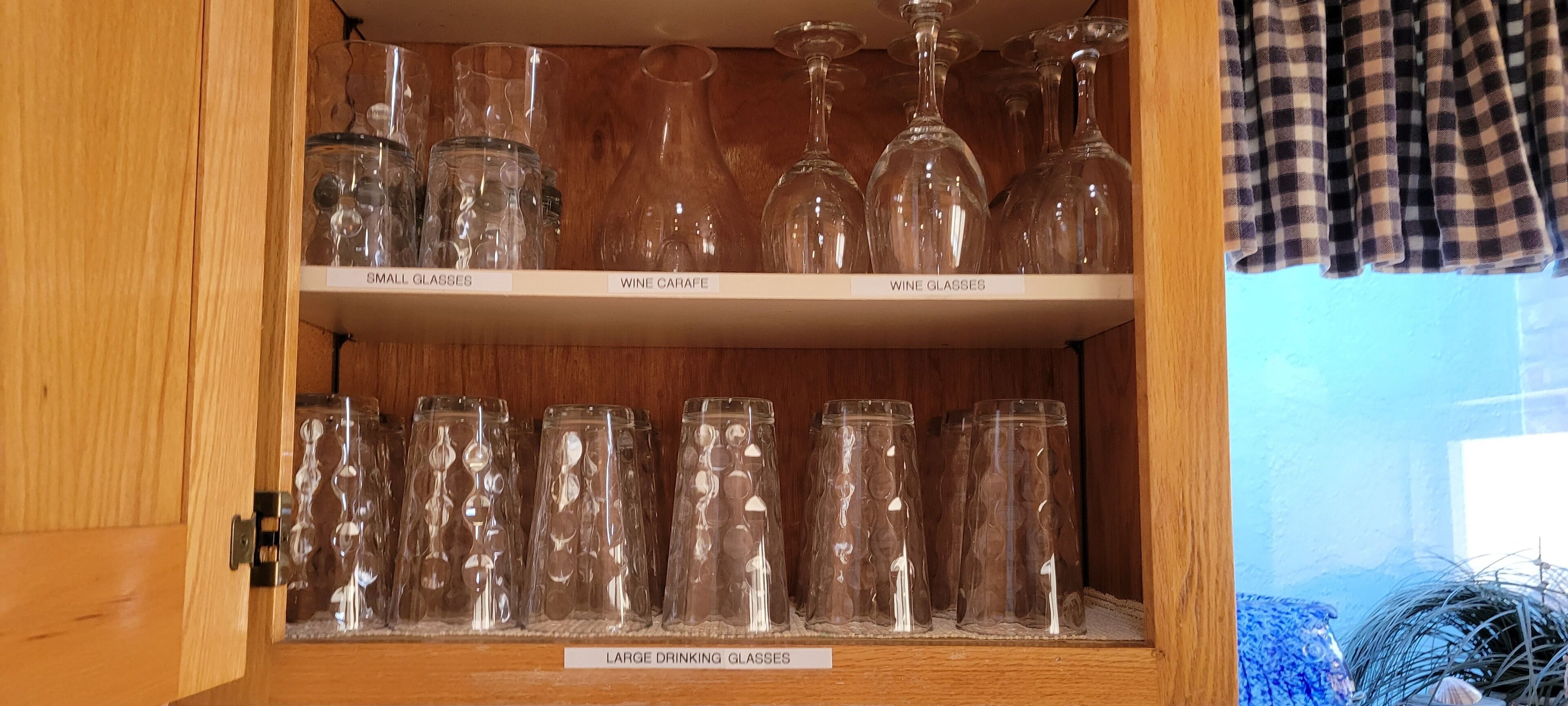 Ett träskåp med hyllor märkta med texten ”ALLA GLAS”, ”VINARA”, ”VINGLAS” och ”STORA DRICKSGLAS”.