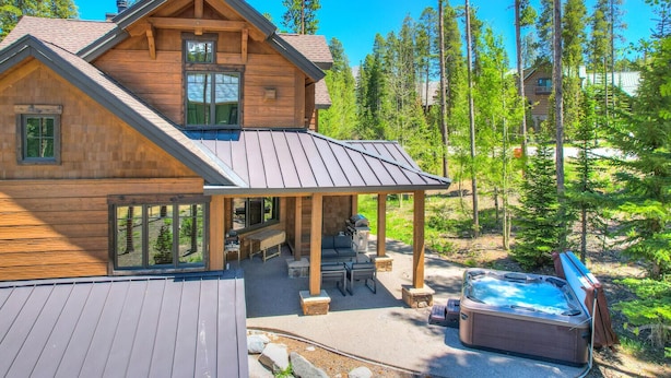 Une cabane en bois dotée d’un patio couvert, de meubles d’extérieur et d’un bain à remous.