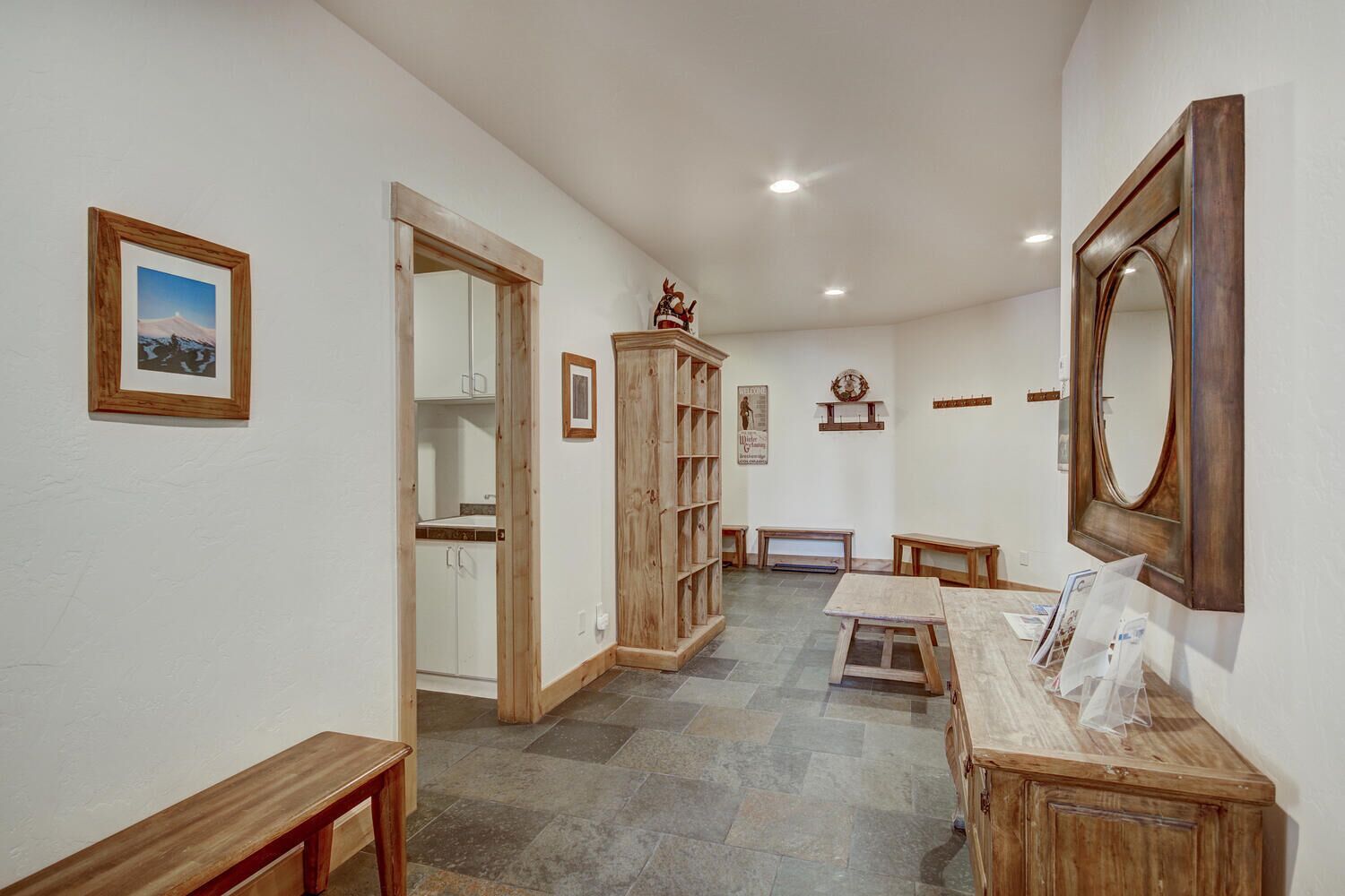 A hallway with a wooden cabinet, a mirror, and a framed picture on the wall.