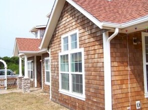 A two-story house with a red-tiled roof, white-framed windows, and a stone pillar. - Florence Oregon, Enjoy Walks on the Beach or Relax by the Fire (Florence)