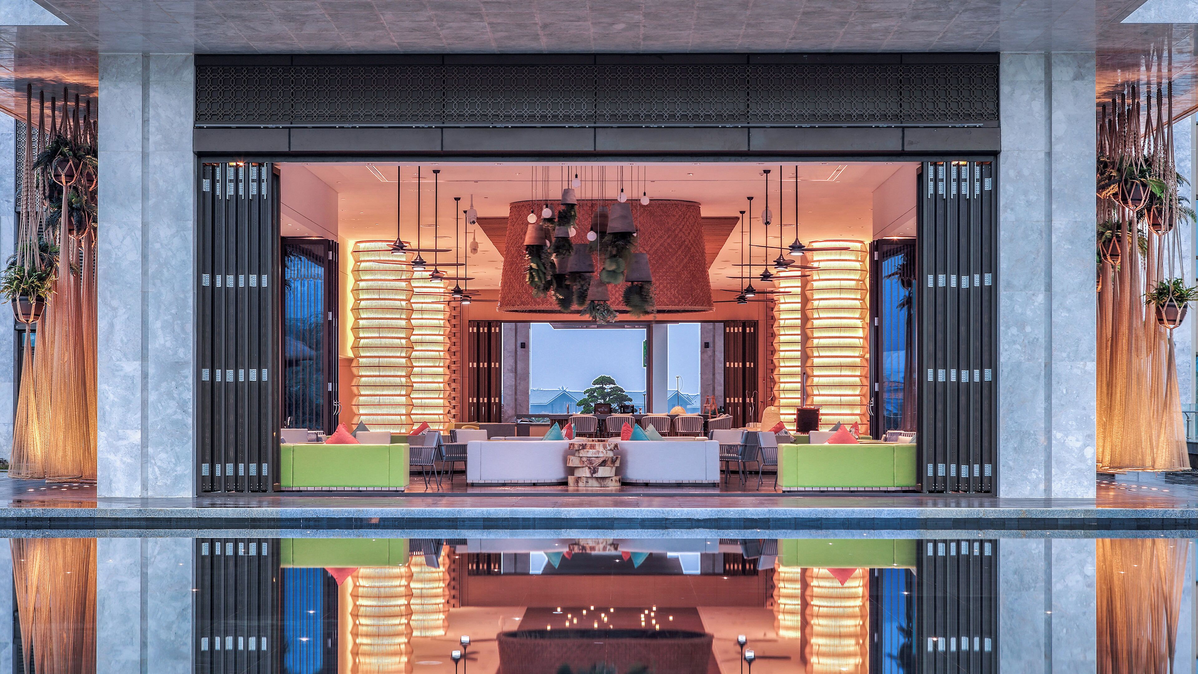 Un vestíbulo moderno con zona de estar, ventanas amplias y una piscina reflectante.