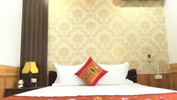 Habitación de hotel con cama, mesita de noche, lámpara, aire acondicionado y una pared con estampado floral.