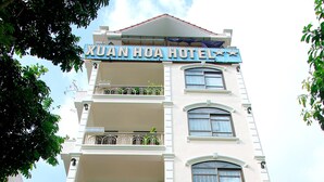 Un hotel de varios pisos con balcones, un restaurante y un letrero que indica que es el Hotel Xuan Hoa.