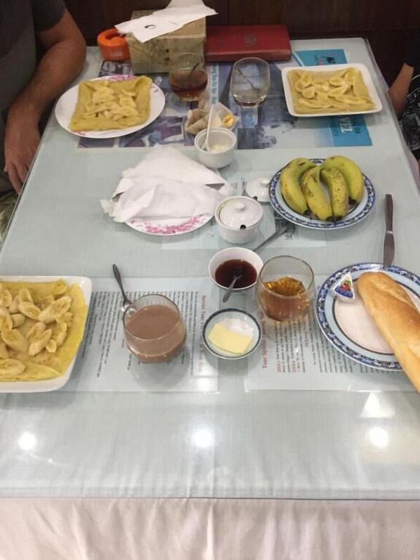 A table set with various dishes including crepes, bananas, and a baguette, along with condiments and a beverage. - Xuan Hoa Hotel (Hoa Lu)