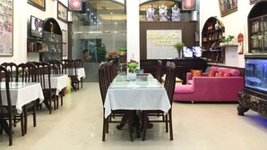 Un vestíbulo de hotel con comedor, una mesa de recepción y un área de estar con un acuario.