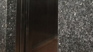 Interior de un ascensor con paredes metálicas y un panel de control a la derecha.